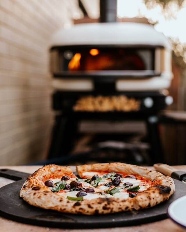Fresh Neapolitan-style pizza with charred crust and toppings in front of a Gozney Dome oven