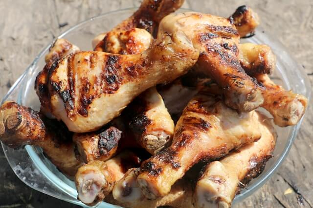 A close-up shot of roasted chicken legs in a glass bowl