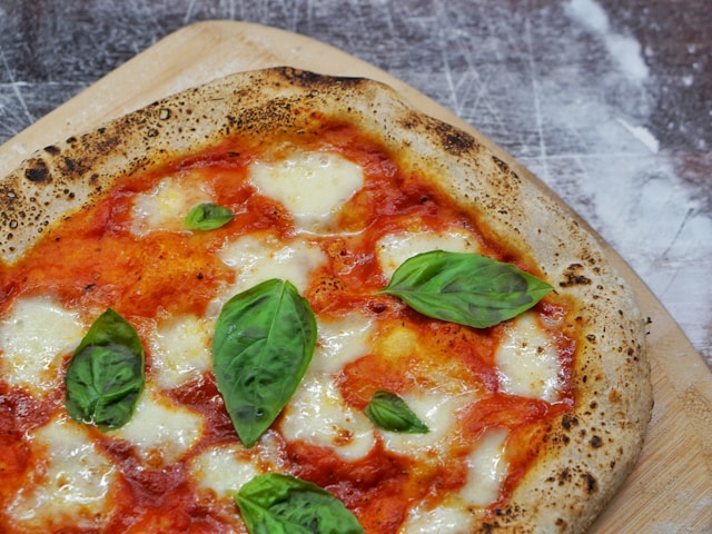 Neapolitan-style Margherita pizza with puffy crust, fresh mozzarella, tomato sauce, and basil leaves