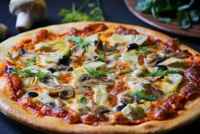 homemade pizza baked in a home oven with mushrooms olives and melted cheese