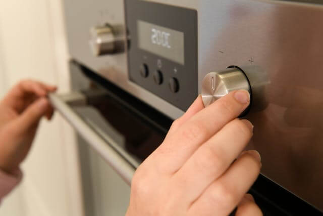 adjusting oven temperature knob before preheating for pizza baking