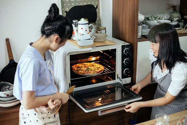placing homemade pizza into oven during baking