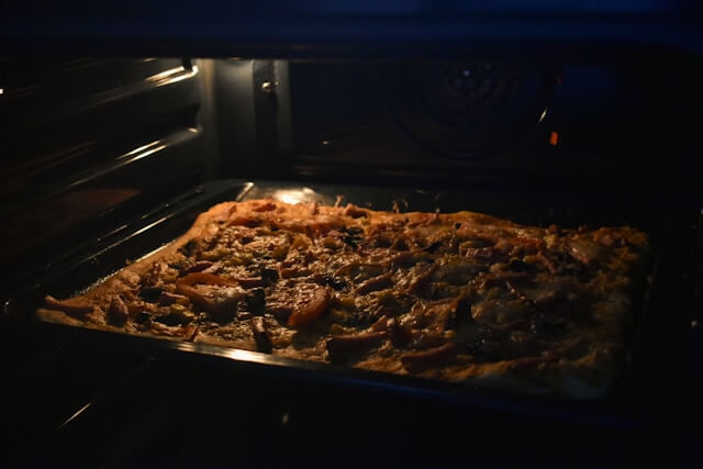 Pizza baking on a tray inside a home oven