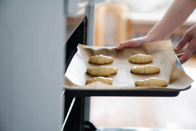 Tray of raw croissant dough being placed into the oven before baking